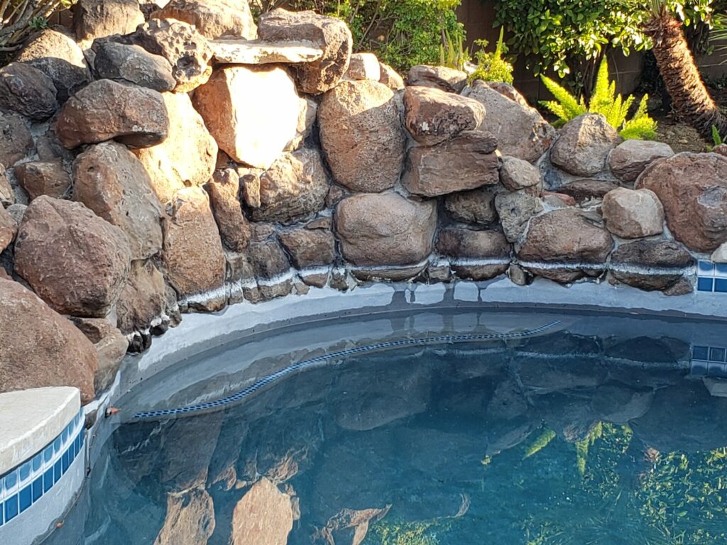 Rock landscaping and blue tile surrounding the pool have 20 year old calcium deposits and stains on them.